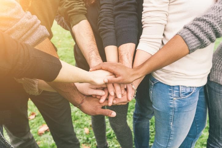 A group of friends holding hands to combat loneliness